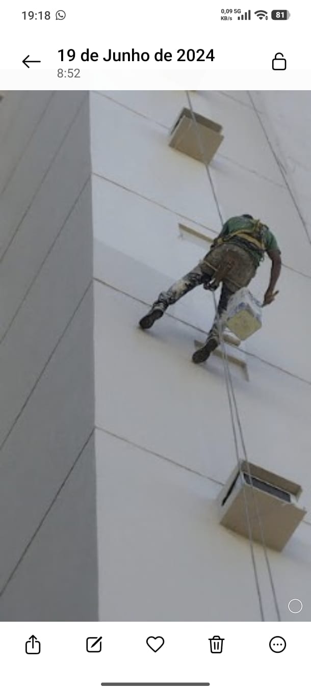 Pintor profissional em balancinho aplicando tinta na fachada de prédio em Vitória ES