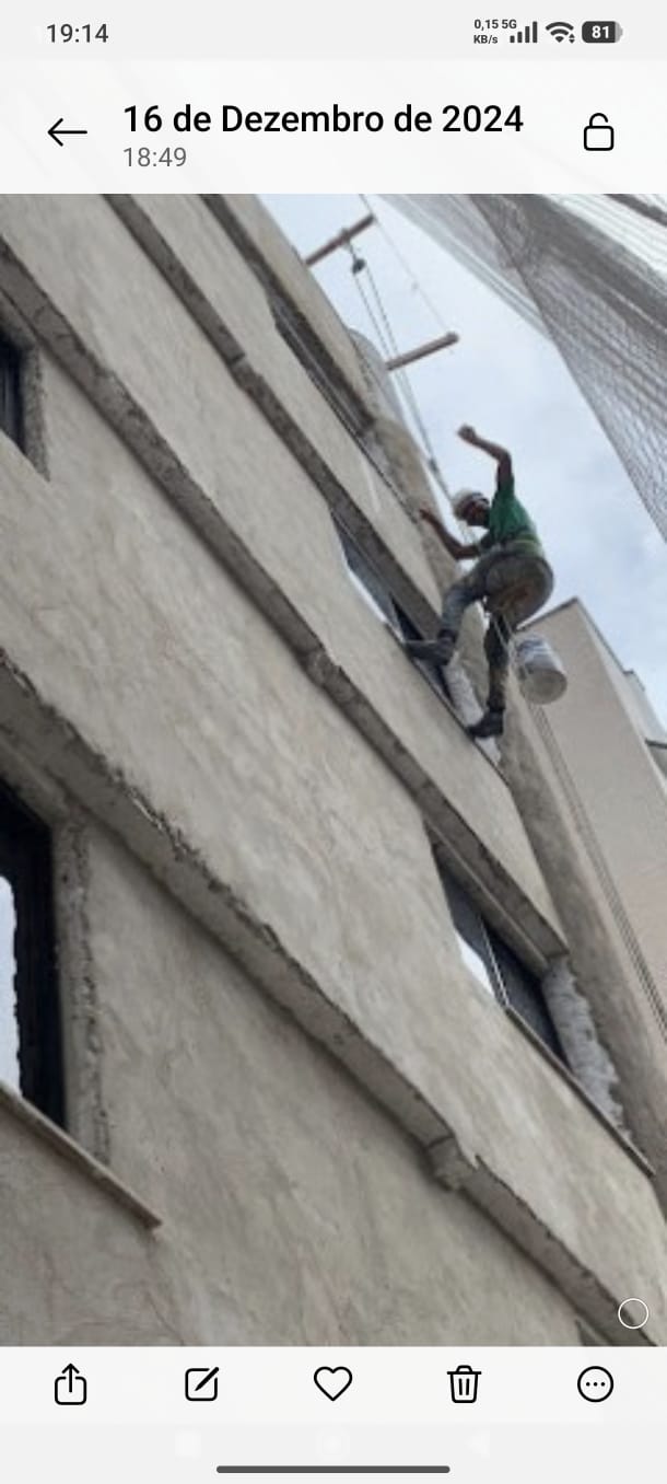 Profissional avaliando estado da fachada de prédio antes da pintura no ES